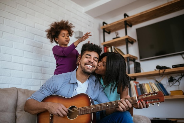 Família se divertindo tocando violão e cantando em casa.