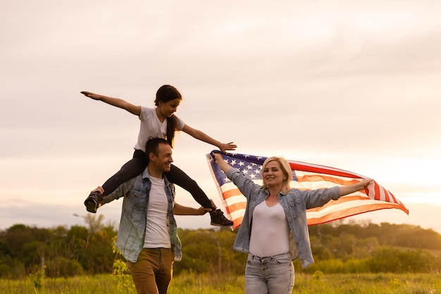 família segurando uma bandeira americana em um campo.