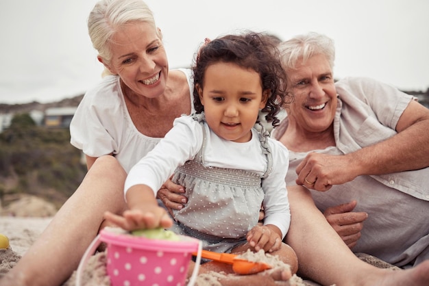 Foto família sênior com menina brincando na areia da praia juntos para férias ao ar livre bem-estar e desenvolvimento infantil avós avós cuidam e amam o bebê ou as pessoas relaxam nas férias ou na aposentadoria