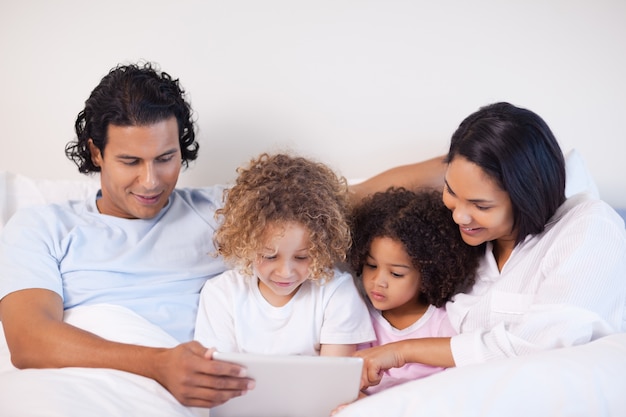 Familia sentada en la cama navegando por la web