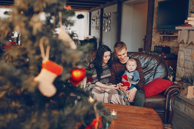 Foto família sentada no sofá com árvore de natal fora de foco na frente