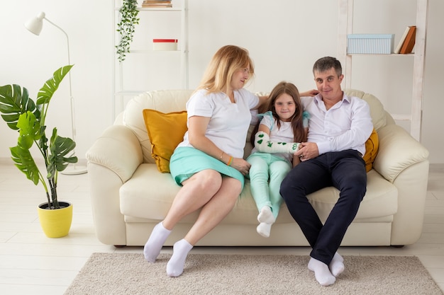 Familia sentada en el sofá de su sala de estar, la hija tiene una lesión en la mano, pero ella es feliz de estar juntos