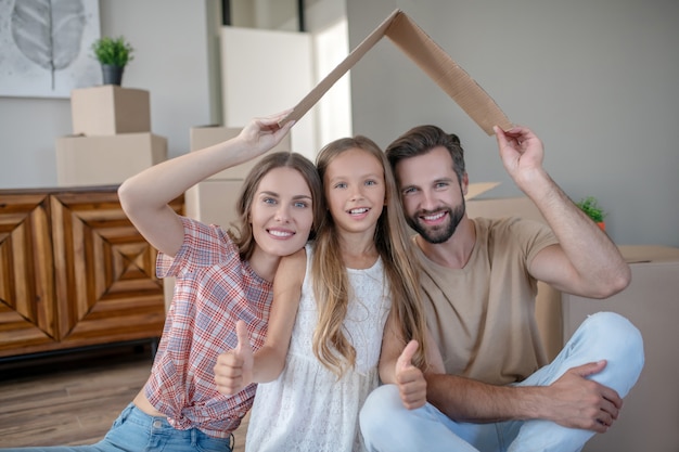 Familia sentada bajo techo de papel y sonriendo