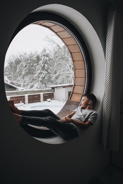 Foto la familia está sentada en la ventana y mirando el bosque de invierno. buen espíritu de año nuevo. mañana en pijama.