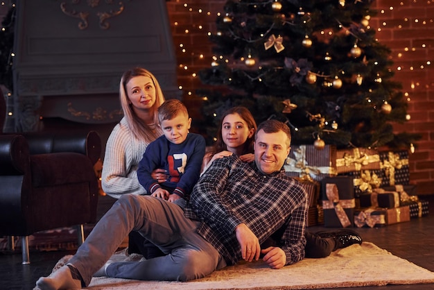 Família sentados juntos na sala decorada de natal com árvore de ano novo.