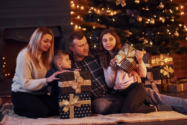 Família sentados juntos na sala decorada de natal com árvore de ano novo.