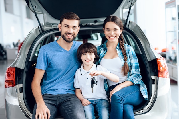 La familia se sentó en el baúl del auto y sonrió.