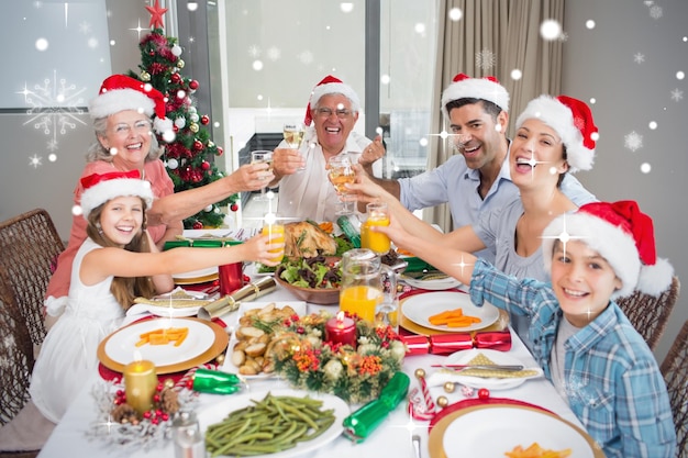Familia con sombreros de Papá Noel brindando copas de vino en la mesa de comedor