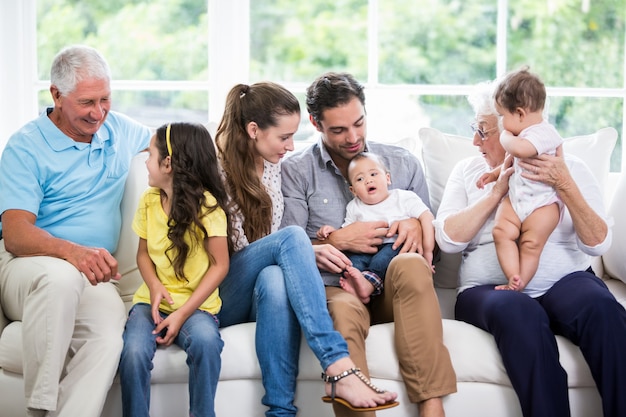 Familia sonriente con abuelos sentados en el sofá