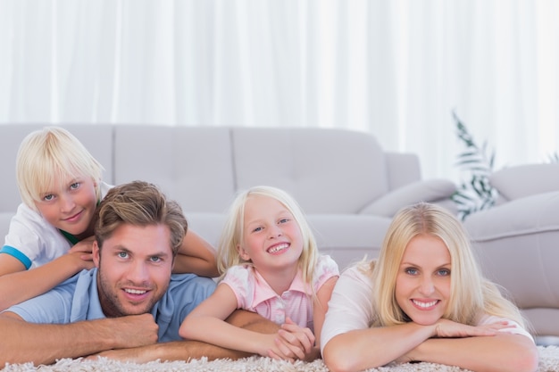 Familia sonriente acostada en la alfombra