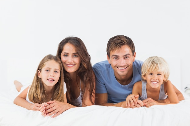 Familia sonriente acostada en una cama