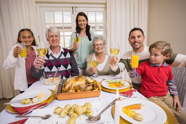 Familia sonriente brindando a la cámara durante la cena de Navidad