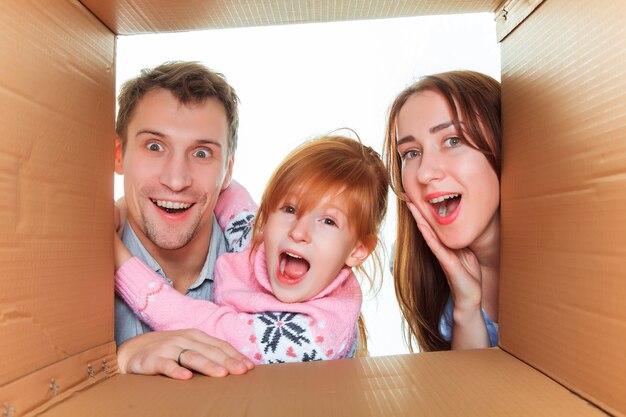 La familia sonriente en una caja de cartón lista para mudarse