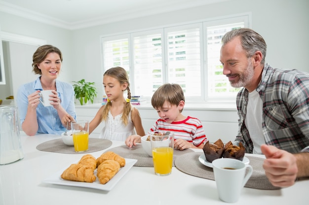 Familia sonriente desayunando en la cocina