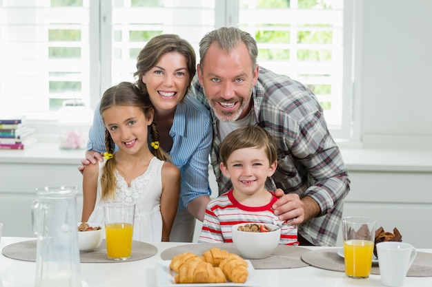 Familia sonriente desayunando en la cocina