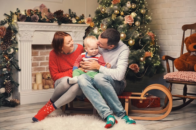 Familia sonriente feliz en el interior de una casa en el fondo del árbol de Navidad con regalos