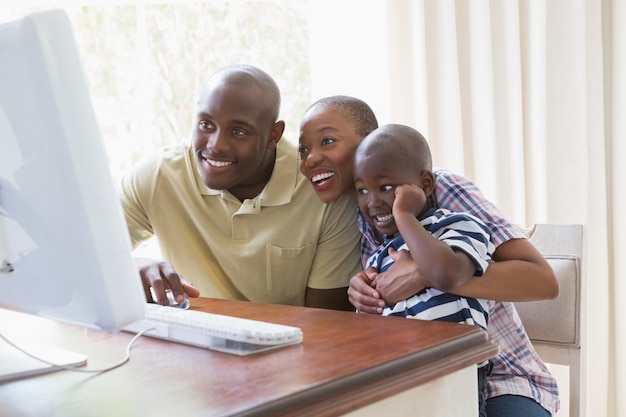 Familia sonriente feliz que charla con la computadora