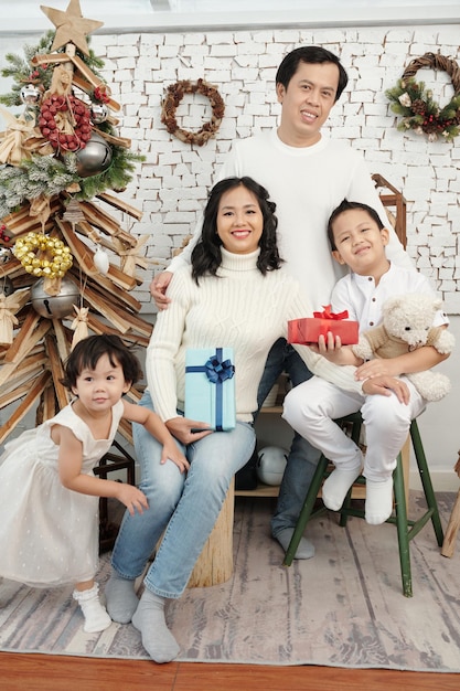 Familia sonriente feliz con regalos sentado en el árbol de Navidad en casa