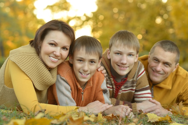 Familia sonriente feliz relajándose en el bosque de otoño