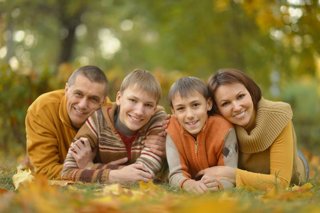 Familia sonriente feliz relajándose en el bosque de otoño