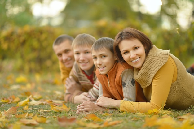 Familia sonriente feliz relajándose en el bosque de otoño