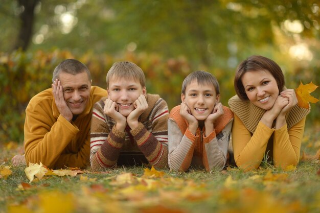 Familia sonriente feliz relajándose en el bosque de otoño