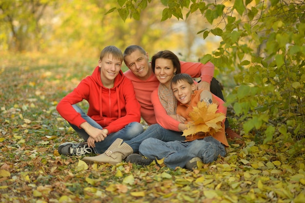 Familia sonriente feliz relajándose en el bosque de otoño