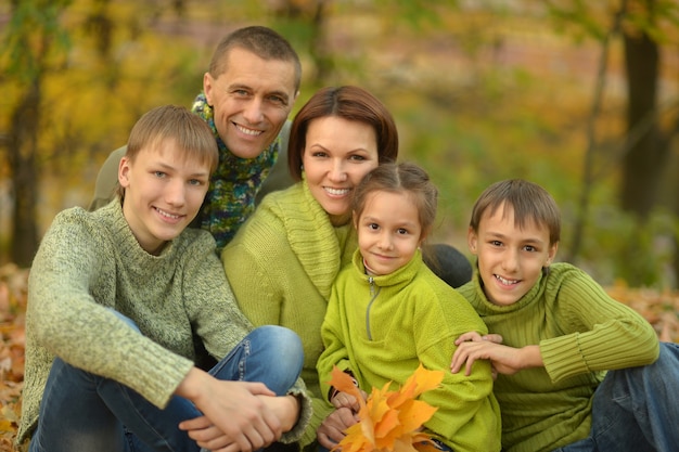 Familia sonriente feliz relajándose en el bosque de otoño