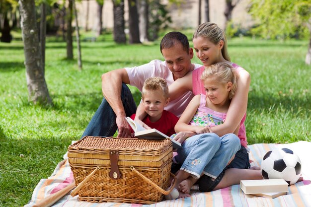 Familia sonriente leyendo mientras toma un picnic