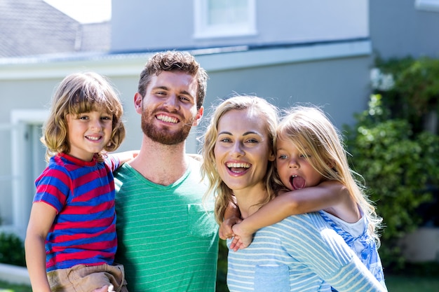 Familia sonriente de pie contra la casa