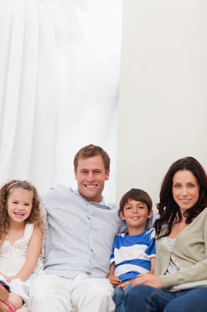 Familia sonriente sentada en el sofá junto