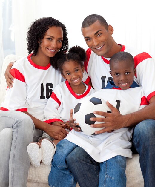 Familia sonriente sosteniendo un balón de fútbol