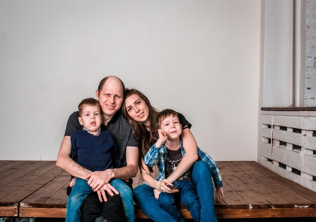 Foto familia sonriente sosteniendo la forma de la casa mientras está sentada en el suelo de madera en casa