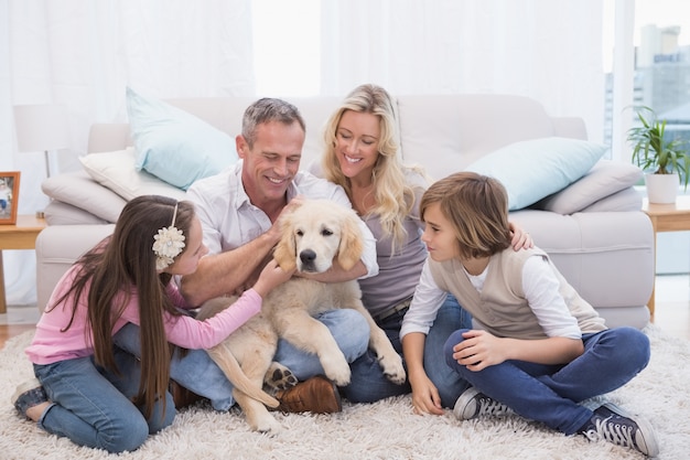 Familia sonriente con su mascota labrador amarillo en la alfombra