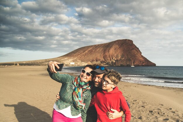 Familia sonriente tomando una selfie en la playa contra el cielo