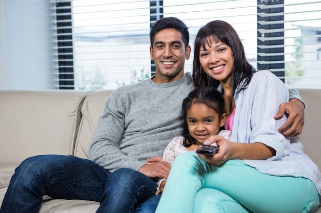 Familia sonriente viendo la televisión en el sofá