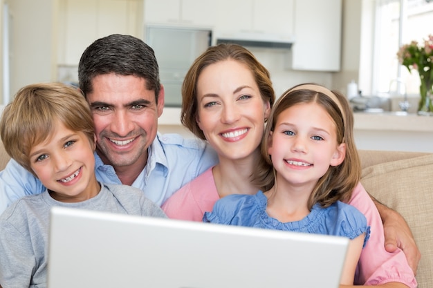 Foto família sorridente com laptop em casa