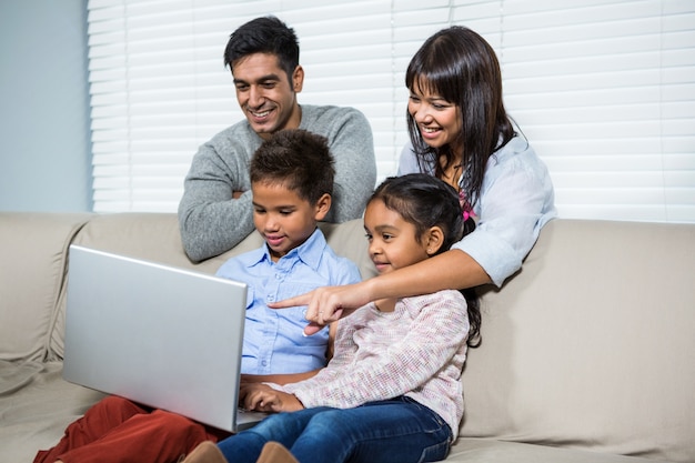 Família sorridente com laptop no sofá