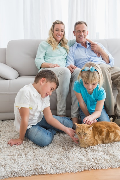 Família sorridente com o gato gengibre no tapete