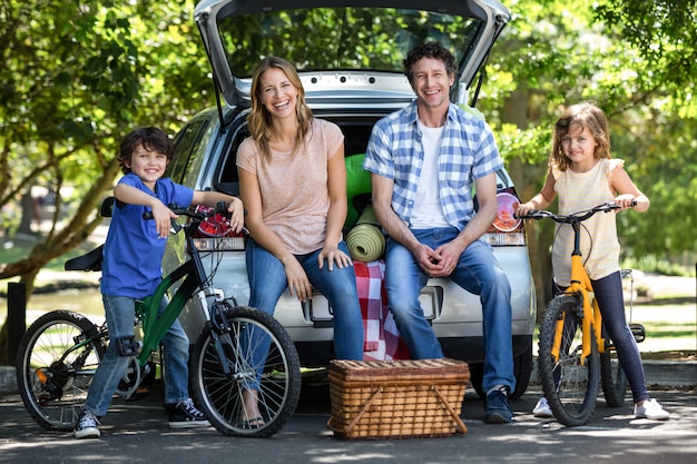 Família sorridente na frente de um carro