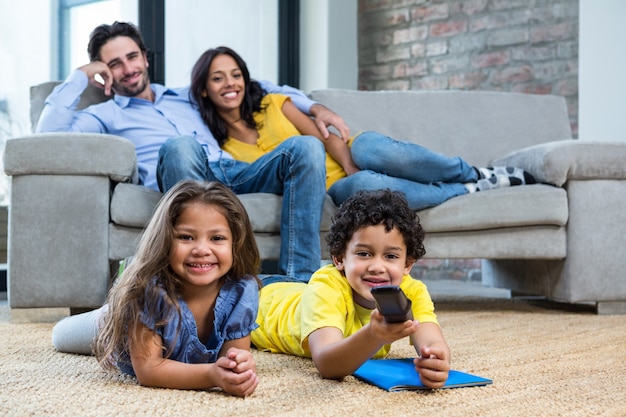 Família sorridente na sala de estar com televisão