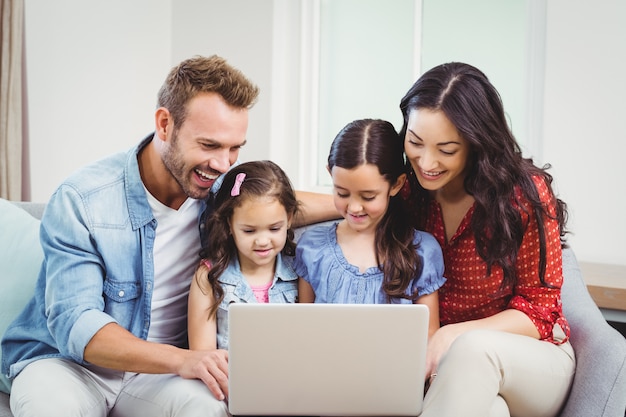 Foto família sorrindo e olhando no laptop no sofá