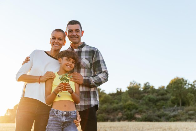 Família sorrindo enquanto posava ao ar livre no campo com uma planta