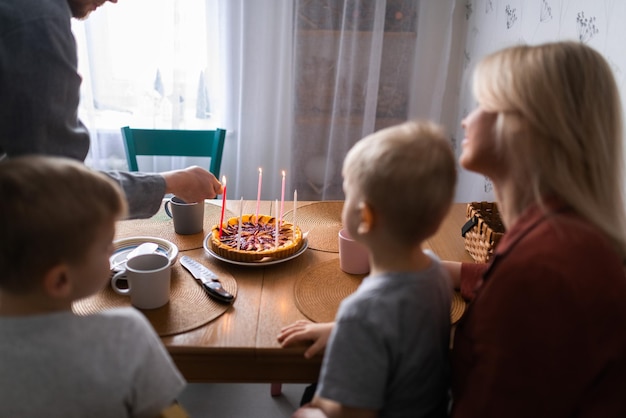 Família sorrindo enquanto queimava velas na torta durante a festa de aniversário em casa