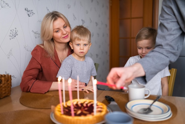 Família sorrindo enquanto queimava velas na torta durante a festa de aniversário em casa