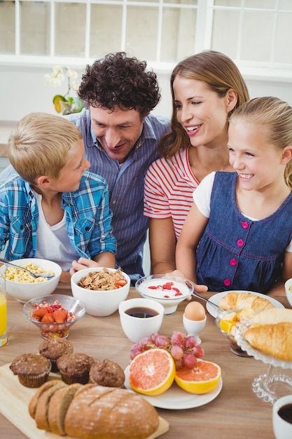 Família sorrindo enquanto tomando café da manhã na mesa