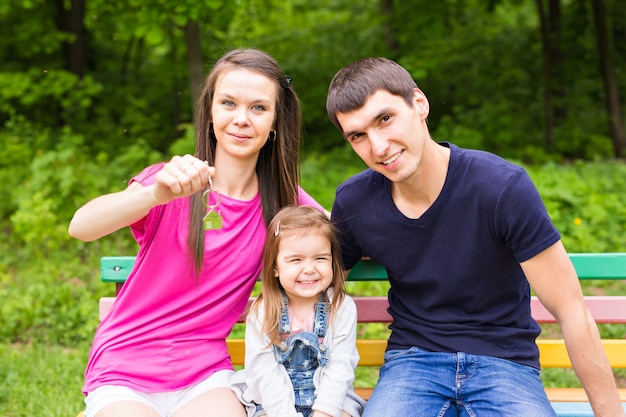 Familia sosteniendo llaves y sonriendo al aire libre