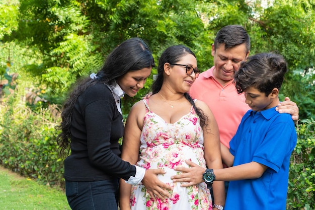 La familia sostiene las manos de la madre en su vientre embarazado
