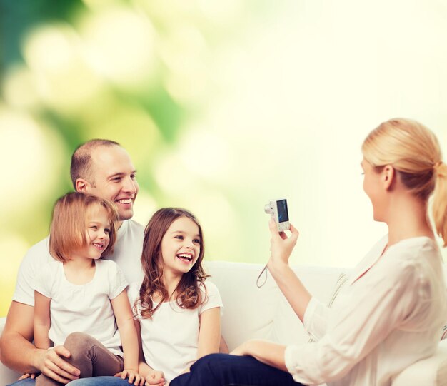 familia, tecnología, ecología y gente - madre, padre y niñas sonrientes con cámara sobre fondo verde