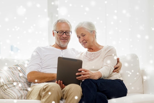 família, tecnologia, idade e conceito de pessoas - casal sênior feliz com computador tablet pc em casa